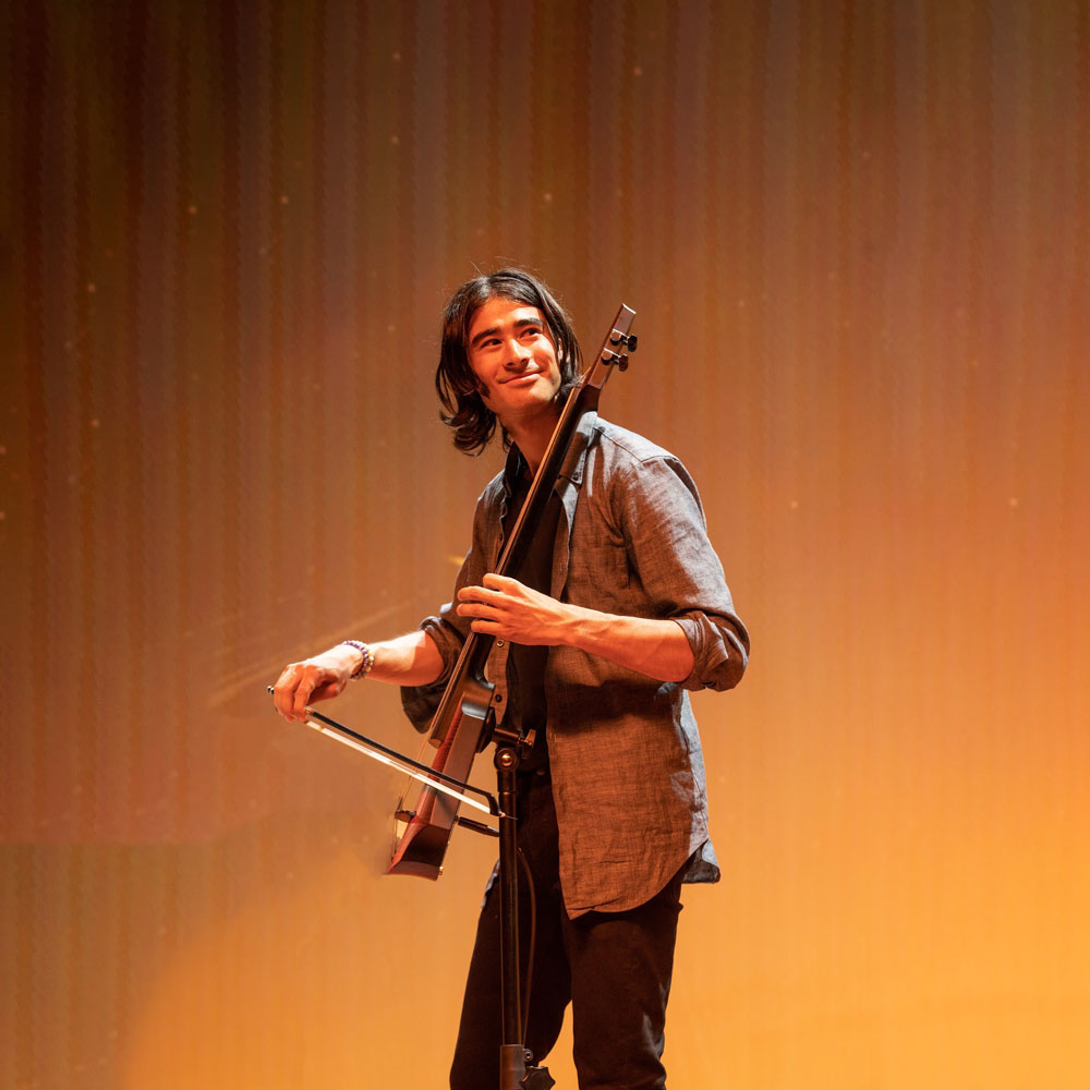 Photo of Dan Gorelick playing a plug-in string instrument fixed to a stand. 